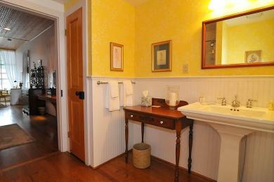 hotel guest room bathroom with hardwood floors baseboard paneling sink table and mirror with yellow painted walls