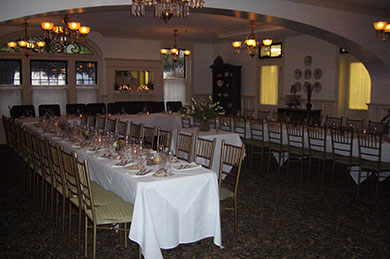 hotel meeting room with long tables with chairs set for dining with hanging chandeliers