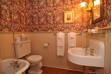 hotel bathroom tub sink toilet with floral wallpaper mirror and lights on wall