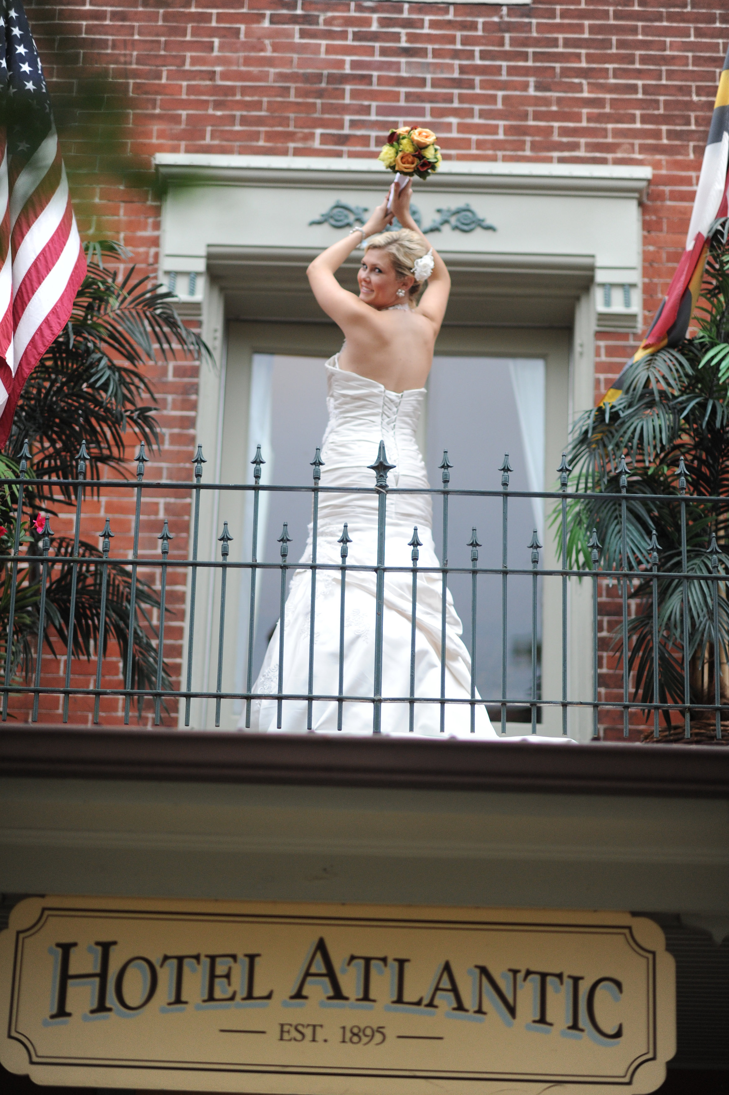 Bride standing on porch of Atlantic Hotel holding bouquet in Berlin MD