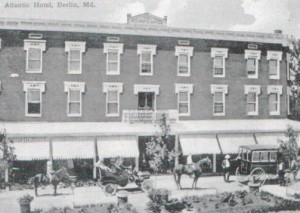 black and white historical image of atlantic hotel with horses and old cars outside