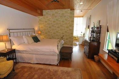 cottage bedroom with iron bed and white comforter dresser and view of seating area
