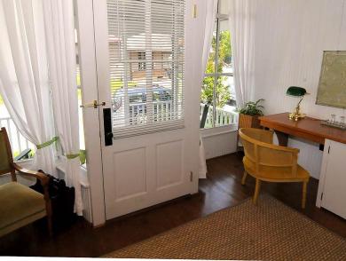 inside entrance of cottage with white front door hardwood floors and wooden desk with chair