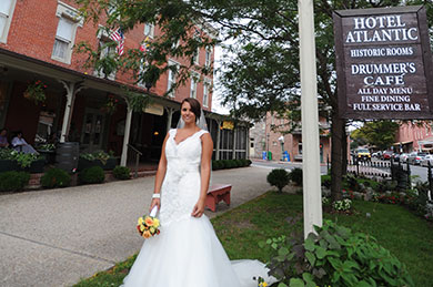 bride standing outside hotel by drummer's cafe sign on lawn